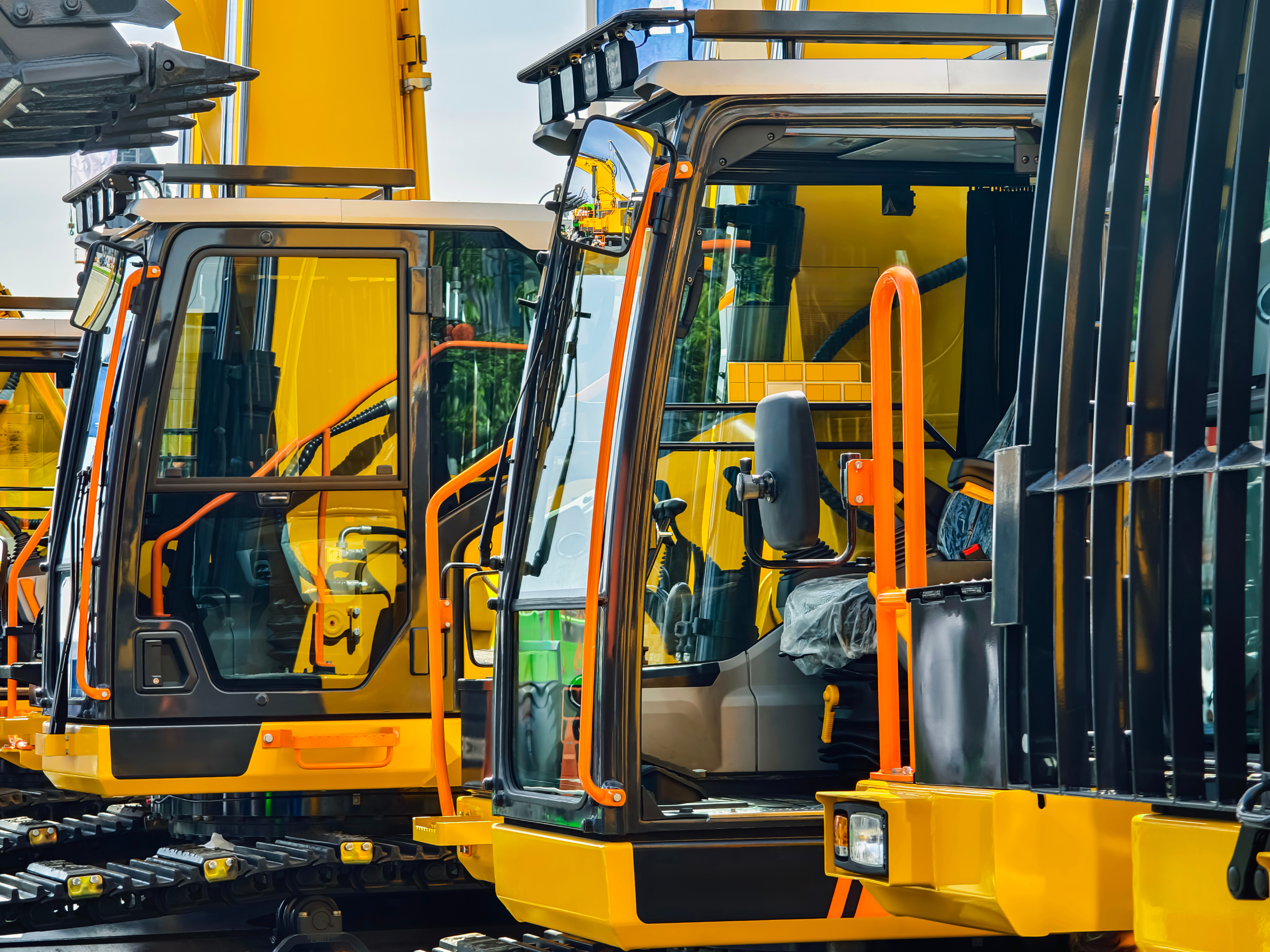 Yellow industrial forklifts parked side by side with open cab doors