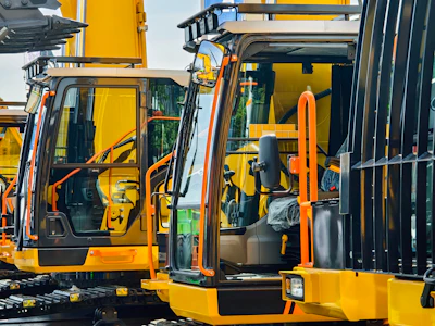 Yellow industrial forklifts parked side by side with open cab doors