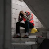 Construction worker sitting on stairs, head in hands, yellow hard hat nearby
