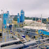 Industrial processing plant with blue and gray machinery, pipelines, and storage tanks