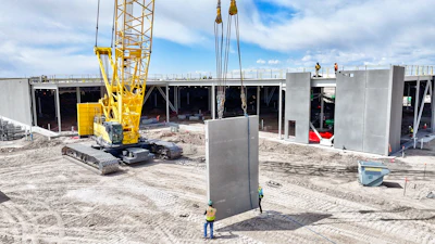Construction site with yellow crane lifting concrete wall panel