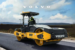 Volvo road roller compacting fresh asphalt on highway with mountain landscape