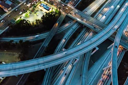 Aerial night view of multi-level highway interchange with illuminated roads and vehicles