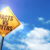 Yellow road sign reading 'Facts vs Myths' against bright blue sky with clouds