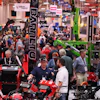 Crowded industrial machinery trade show with red and green equipment displays
