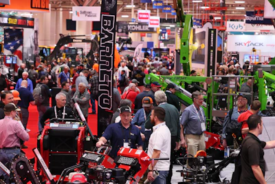 Crowded industrial machinery trade show with red and green equipment displays