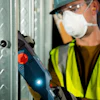 Construction worker wearing safety vest, hard hat, and mask using power tool