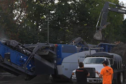 Construction site with blue excavation machinery and workers in orange safety vest