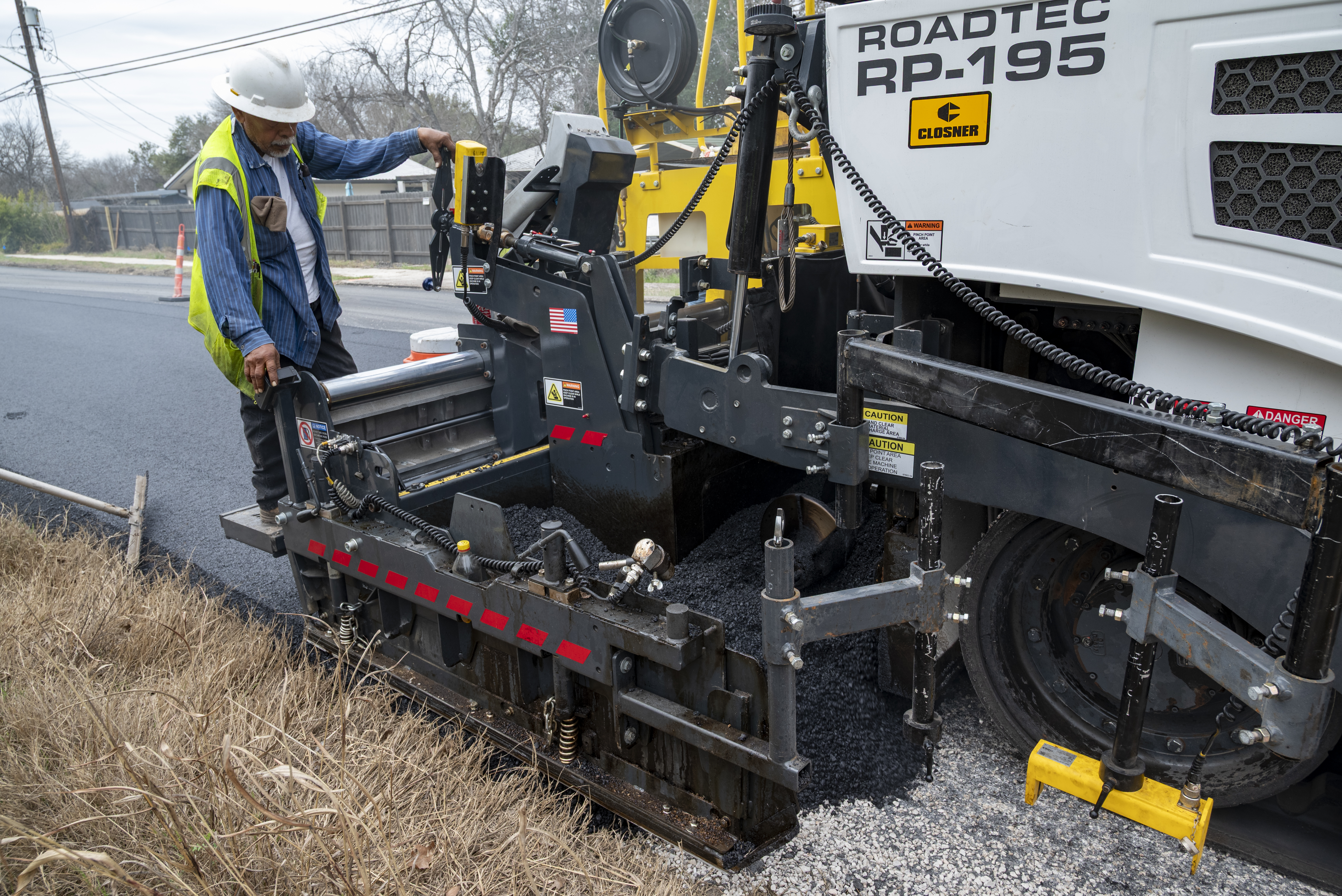 Road construction worker operating Roadtec asphalt paving machine on roadside