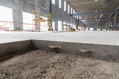 Construction site interior with concrete floor, scaffolding, and exposed building structure