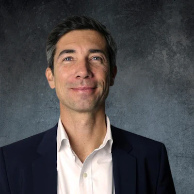 Professional man in navy blazer and white shirt against textured gray background