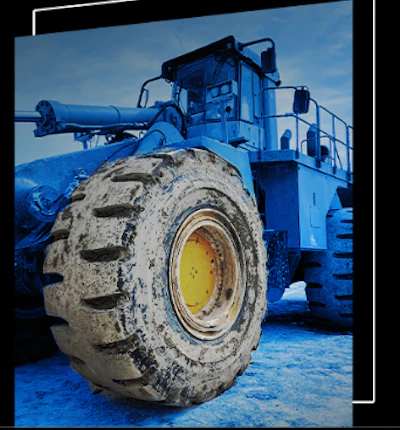 Large blue industrial wheel loader with muddy tire on blue background