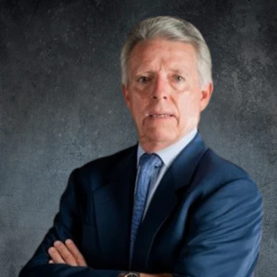 Senior executive in navy suit with crossed arms, standing against textured gray background