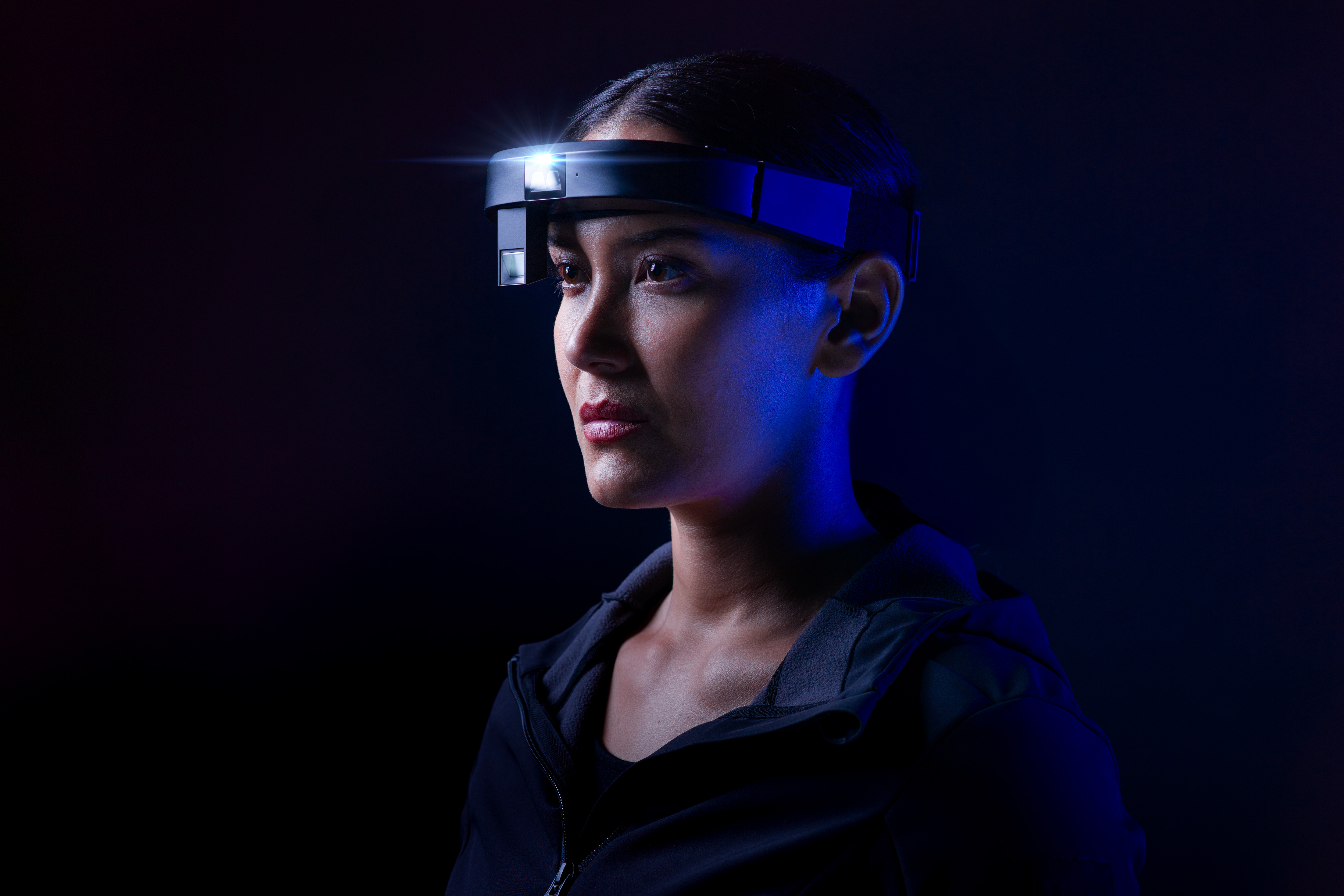 Person wearing high-tech headset against dark blue background