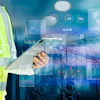 Construction professional with digital technology interface showing industrial data analytics