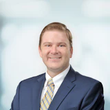 Smiling professional in navy blue suit and striped tie against blurred background