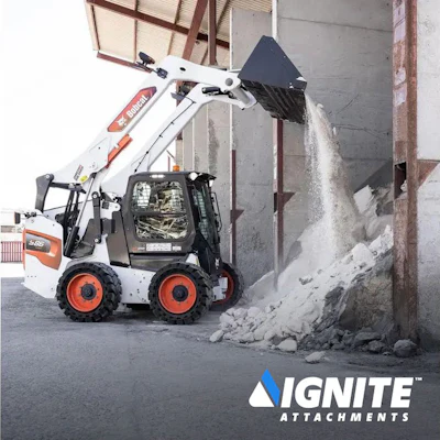 White skid steer loader dumping rocky material inside an industrial warehouse
