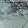 Construction workers pouring concrete on steel rebar foundation using concrete pump