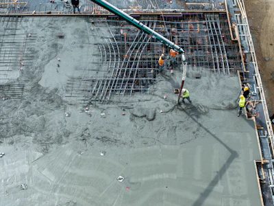 Construction workers pouring concrete on steel rebar foundation using concrete pump