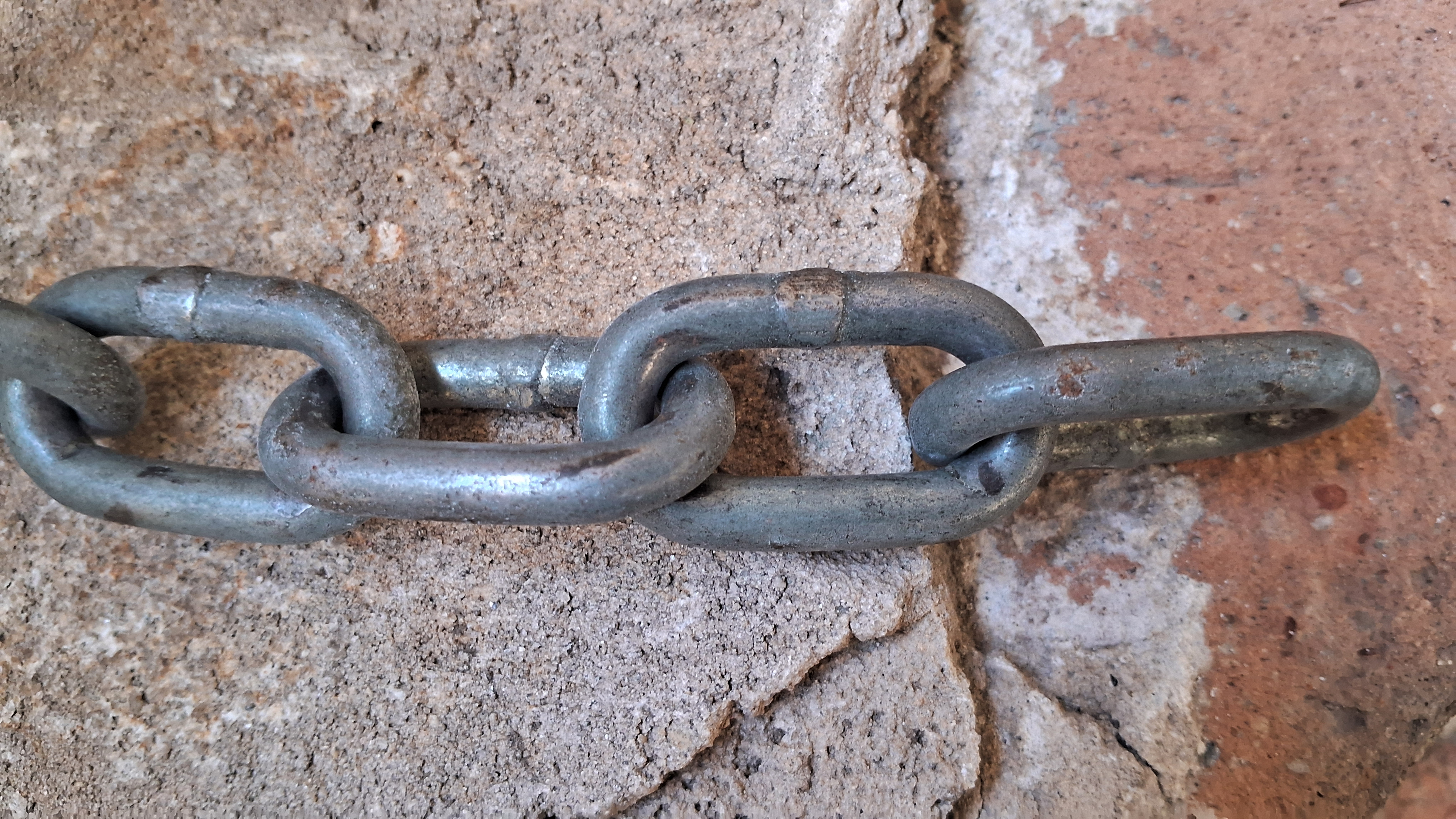 Gray metal chain links connected against weathered stone background