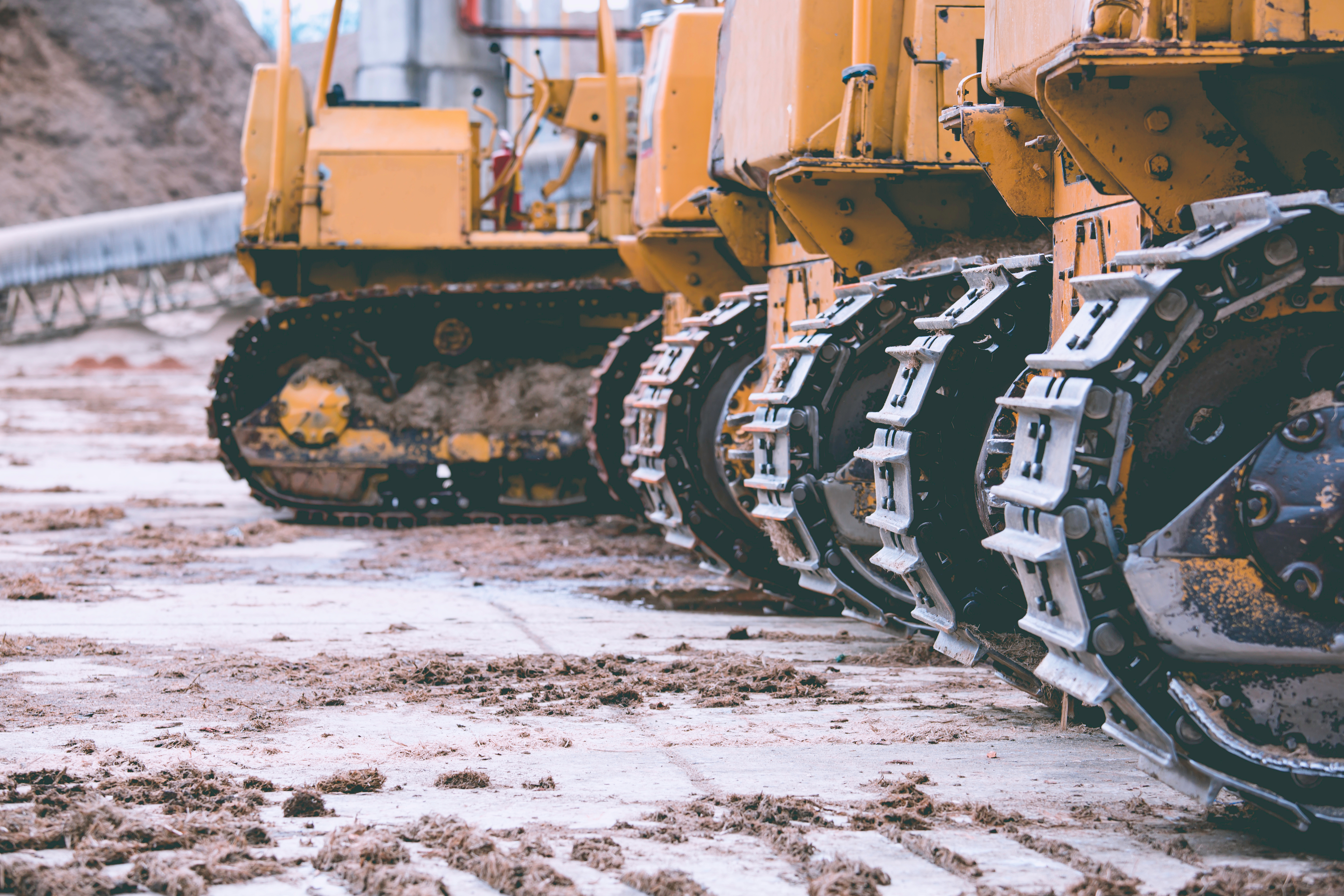 Yellow construction bulldozers with metal tracked wheels on muddy construction site