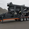 Mobile industrial screening machine with three-axle trailer on gravel lot