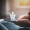 Hand holding smartphone with glowing digital shopping cart icon