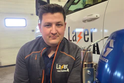 Lazer Line Painting employee in branded gray and orange uniform standing in garage