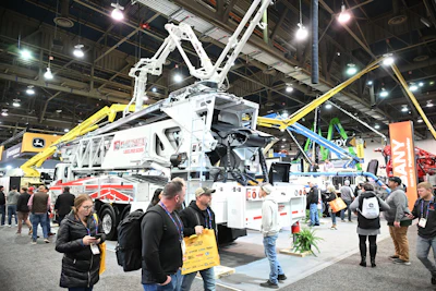 Large white utility truck with extended boom at industrial trade show exhibition