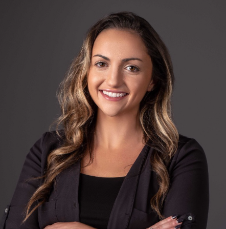 Professional woman smiling in black blazer against gray background Headshot