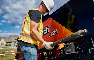 Construction worker operating Ditch Witch JT21 horizontal directional drilling machine outdoors