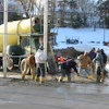 Construction workers pouring concrete beside a yellow cement mixer in winter