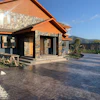 Modern stone and wood house with stamped concrete driveway, mountain landscape background