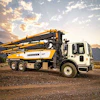 Liebherr concrete pump truck parked on dirt ground with mountain landscape at sunset