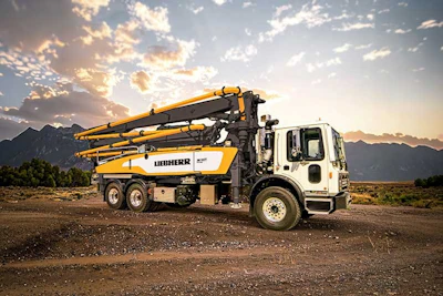 Liebherr concrete pump truck parked on dirt ground with mountain landscape at sunset