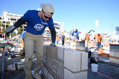 Construction worker laying concrete blocks at an outdoor job site