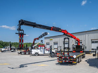 Heavy-duty truck with extended crane mounted on flatbed in industrial parking lot