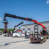 Heavy-duty truck with extended crane mounted on flatbed in industrial parking lot