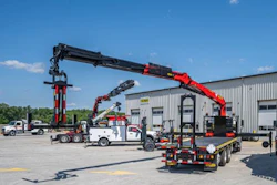 Heavy-duty truck with extended crane mounted on flatbed in industrial parking lot