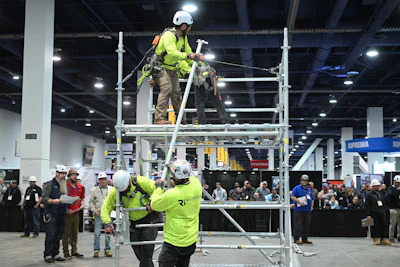 Safety workers assembling scaffolding at industrial trade show conference