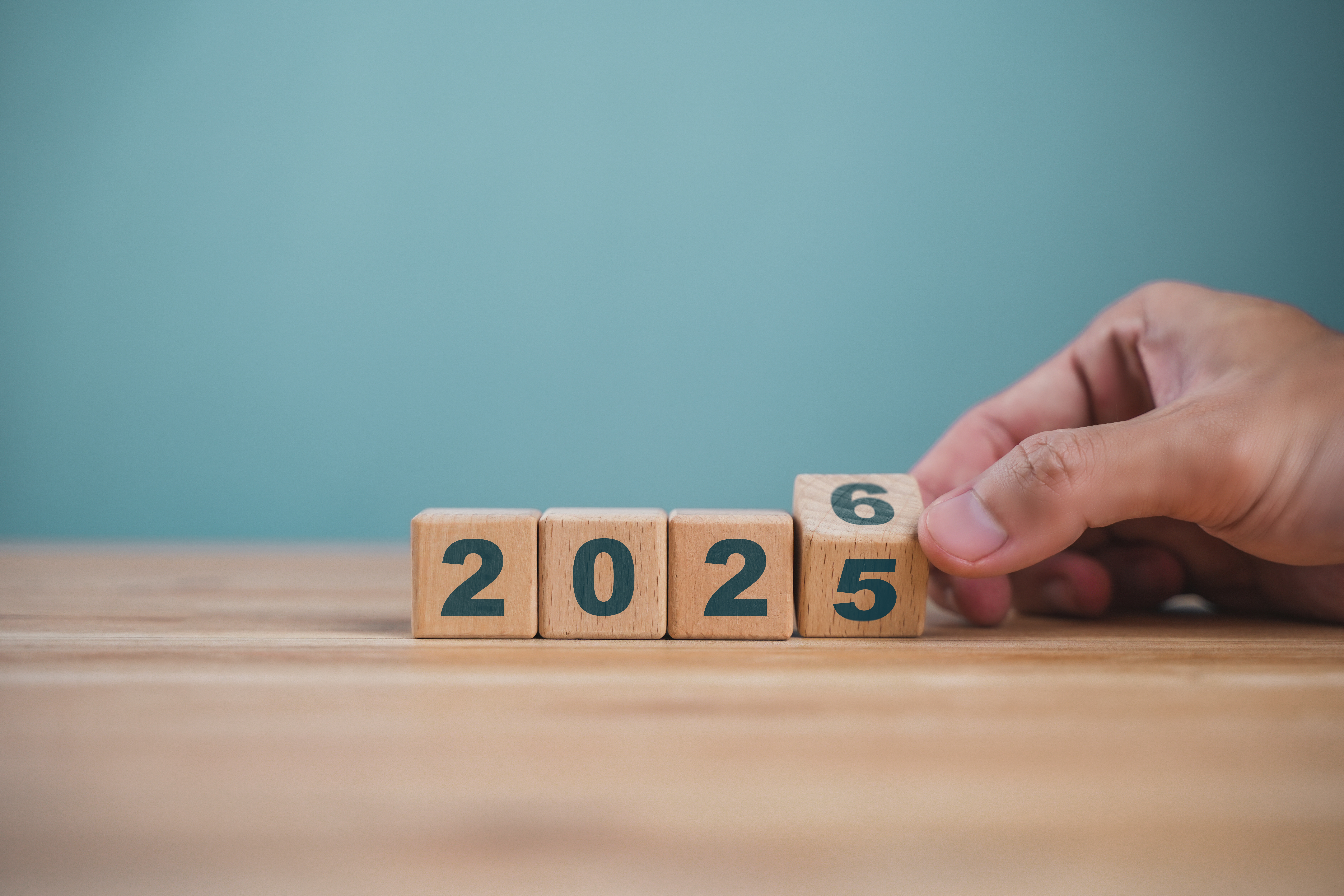 Hand flipping wooden block changing year from 2025 to 2026