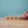 Hand flipping wooden block changing year from 2025 to 2026