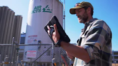 Worker checking equipment near Air CTS industrial storage tank with safety signage