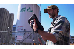 Worker checking equipment near Air CTS industrial storage tank with safety signage