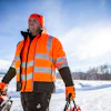 Worker in bright orange safety vest and gloves operating snow equipment