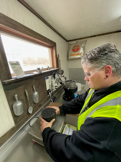 Worker in high-visibility vest weighing material at industrial workstation
