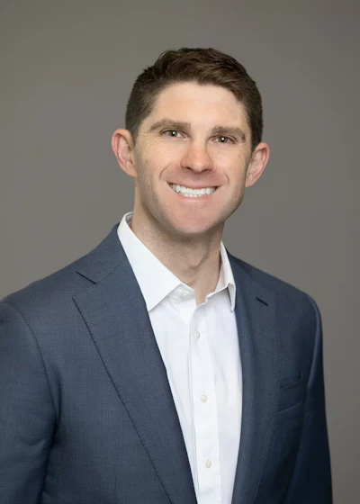 Smiling professional in blue suit and white shirt against neutral background