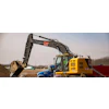 Yellow excavator and blue truck working on construction site with dirt mounds