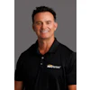 Smiling professional in black HercRentals polo shirt against neutral background