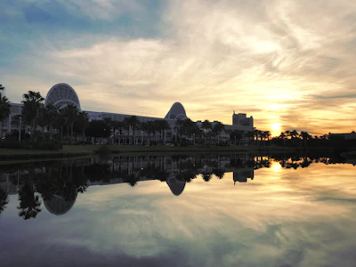 Sunset over convention center with palm trees and water reflection